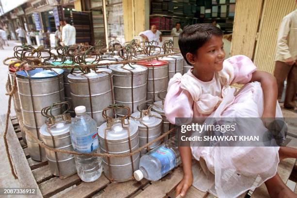 Rina, a nine-year-old girl sits on a richskaw van with lunch boxes to be delivered to offices during the lunch hour at Dhaka, 05 Augest 2002. Rina...