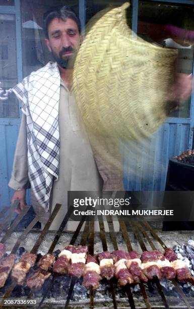 Resturant owner grills meat outside his shop in Kabul 04 May 2002. It is a common practise to grill outside the resturant to attract customers in...