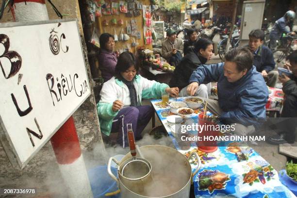 Food vendor serves snail and crab noodles for breakfast to a customer along a street in Hanoi, 03 March 2003. Small and makeshift restaurants are a...