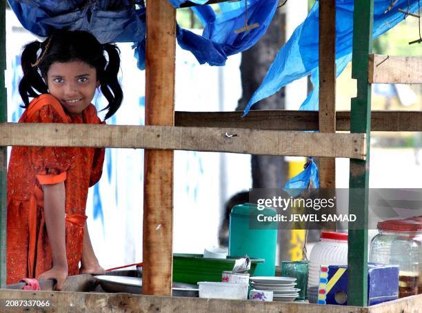 One name), a nine-year-old food vendor, waits for customers in Dhaka, 17 May 2002. Rekha who earns up to 60 Taka daily selling food to the rickshaw...