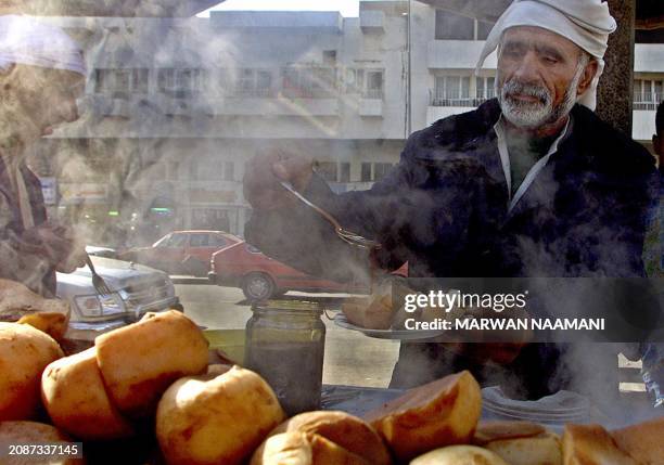 An Iraqi pours some honey over boiled turnips to be served as breakfast for a customer in the heart of Baghdad 24 December 2002. UN weapons experts...