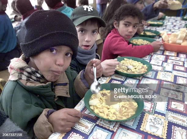 Children of public school No. 355 eat at the school cafeteria in Montevideo, 10 July 2002. Public schools which normally hold classes from March to...