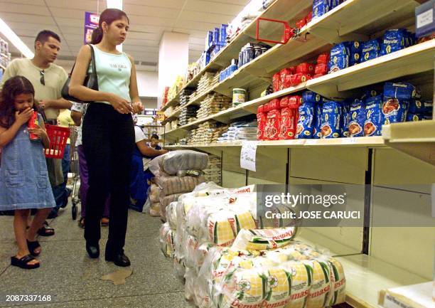 Customers look at shelves in a supermarket, 14 December 2002 in Caracas, as a possible food shortage is feared from the national strike that entered...