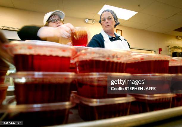 Volunteers Polly Agee of Arlington, Virginia, and Krista Sassaman of Washington, DC, help prepare turkey dinners for people living with HIV/AIDS and...