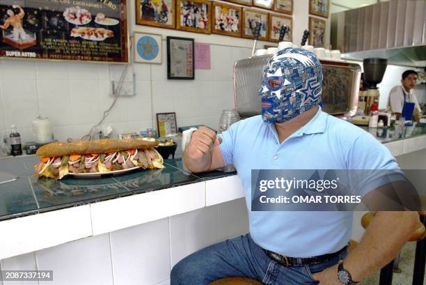 Mexican wrestler "Superastro" poses 21 August with his invention the "Gladiator" hoagie at his "El Cuadrilátero" restaurant in Mexico City. The...