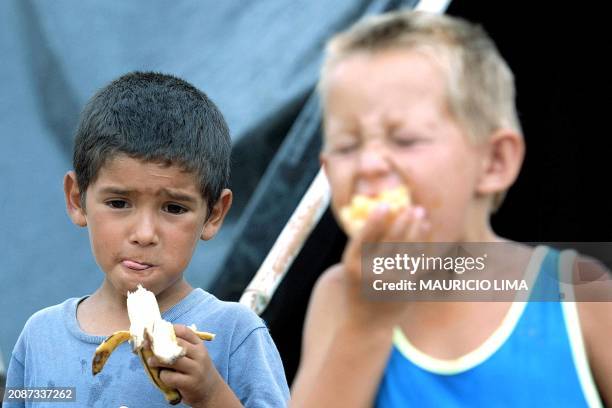 Two boys eat bananas, 31 January 2002, in the camp for Movimiento de los Trabajadores Rurales Sin Tierra , in Porto Alegre, Brazil. Organizers expect...