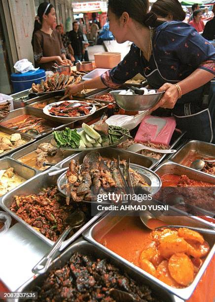 Woman puts a finishing touch on a food display at Jalan Tunku Abdul Rahman, one of the busiest streets in Kuala Lumpur. Most of the stalls only...