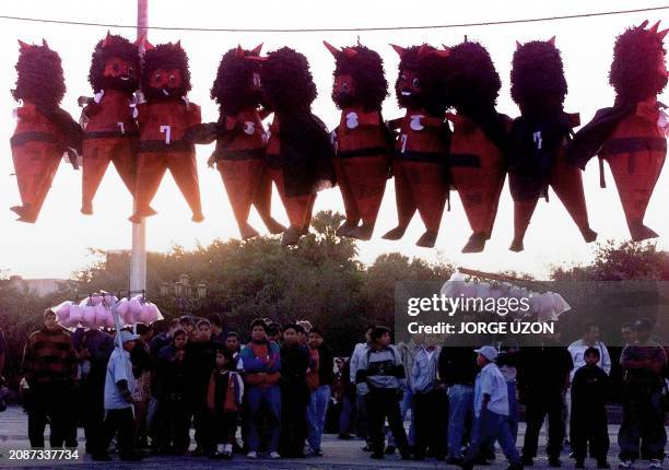 Guatemalans looks at pinatas portraying the devil in Guatemala city 07 December 2000. Guatemaltecos observan pinatas con la figura del diablo en el...