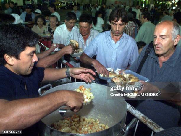 Workers receive food in the Plaza de Mayo, in front of the Presidential residence in Buenos Aires, Argentina, 24 December 2000, Christmas Eve. Un...
