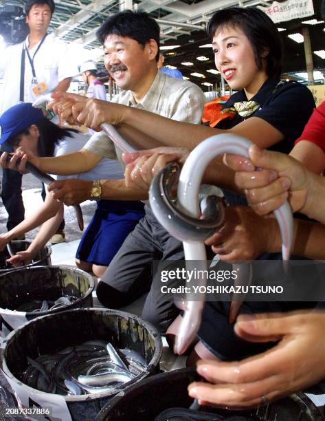 Japan Asia Airways flight attendant Takae Tsuruta and a eel restaurant owner try to catch live eels imported from Taiwan at the new Tokyo...