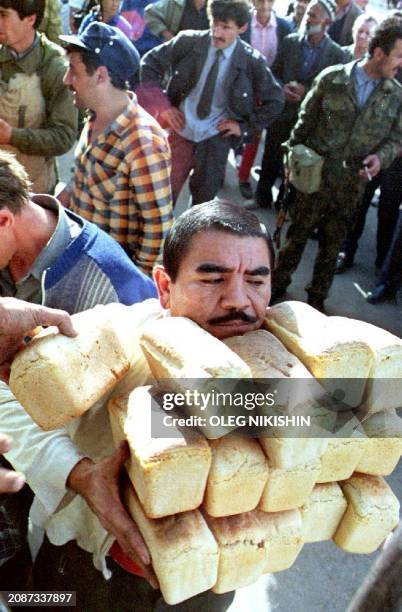 Man carries bread 27 October 1992 after buying it from a street vendor in the Tajik capital where food distribution has become a major problem since...