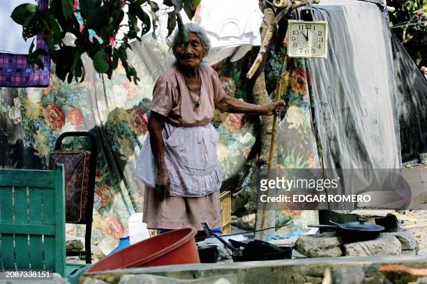 Rosa Esperanza Lopez cooks food 20 February 2001 on the ruins of her house, destroyed by the 13 February earthquake, in Verapaz, El Salvador. Rosa...
