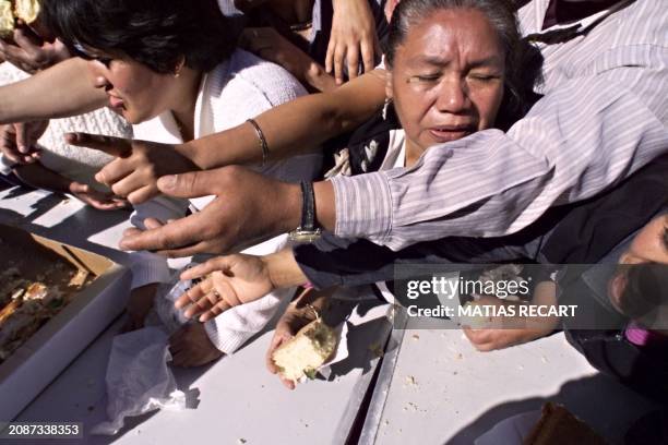 People receive food during a festival 03 January in Mexico City. Un grupo de personas se aprietan para recibir un pedazo de la Rosca de Reyes mas...
