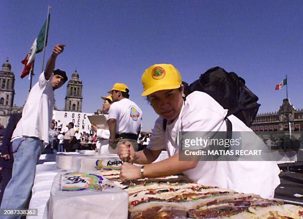 Volunteers work during a festival 03 January in Mexico City. Un grupo de voluntarios cortan la Rosca de Reyes mas grande del mundo para ser...