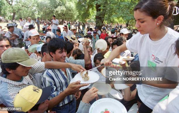 Volunteer woman gives food to farmers in the Metropolitan Seminary, site of previous concentration offered by the Catholic church, 15 March, 2000 in...