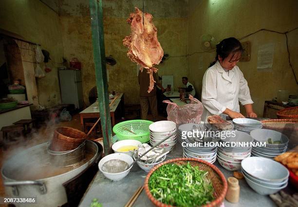 Vendor stands behind piles of soup bowls at her almost deserted Pho restaurant in downtown Hanoi 04 January 2000. Hanoians are boycotting restaurants...