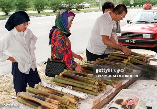 People stop to buy the sticky rice cooked in bamboo shoots, locally known as "lembang", for their break-fasting at a temporary stall set up on the...