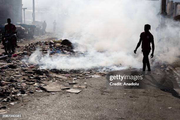 People burn garbage close to the bodies of the dead as at least 10 bodies of gang members lie in the streets following the exchange of gunfire...