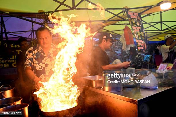 Street vendor cooks Char kway teow as Muslim devotees buy food before breaking their fast during the Islamic holy fasting month of Ramadan in Kampung...