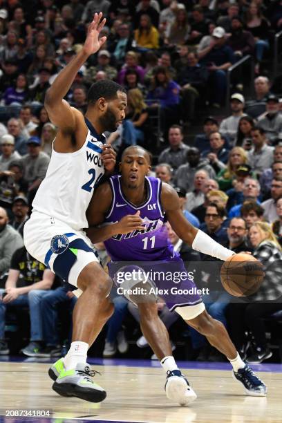 Kris Dunn of the Utah Jazz drives into TJ Warren of the Minnesota Timberwolves during the second half of a game at Delta Center on March 18, 2024 in...