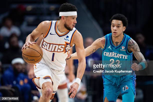 Tre Mann of the Charlotte Hornets guards Devin Booker of the Phoenix Suns in the first quarter during their game at Spectrum Center on March 15, 2024...