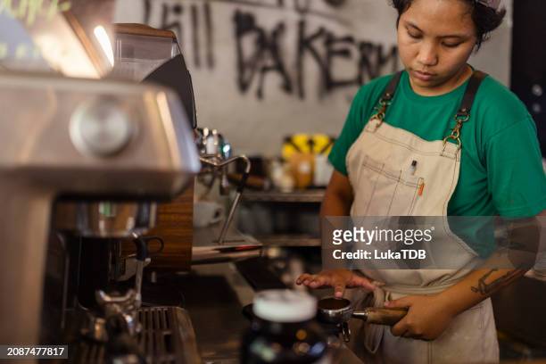 female baker making a coffee using a steaming hot coffee machine in a bakery - hot housewives stock pictures, royalty-free photos & images
