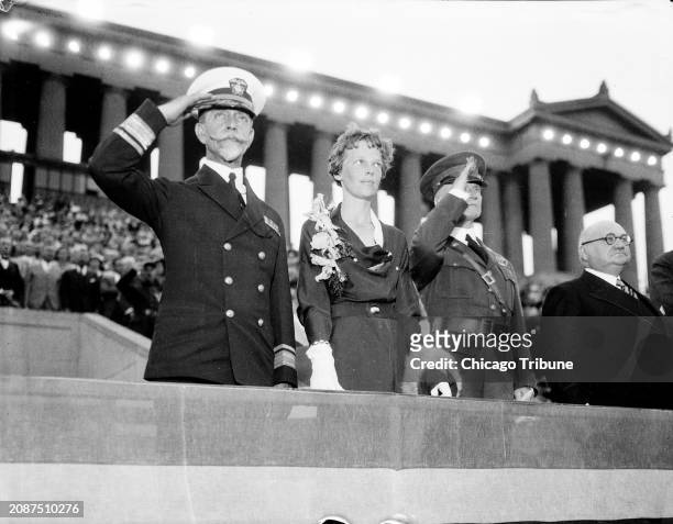 Rear Adm. Walter Crosley, from left, Amelia Earhart and Maj. Gen. Frank Parker salute the flag on the reviewing stand at the George Washington...
