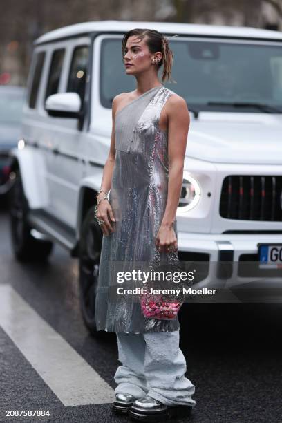 Clara Berry is seen wearing a one-sleeved silver dress made of metal, with light-coloured baggy jeans with a used look underneath, high silver...
