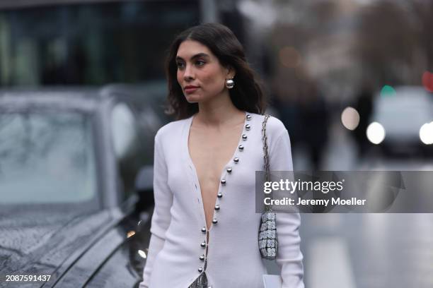 Fer Millan Delaroiere is seen wearing a long silver metallic skirt by Rabanne, a long white cardigan with a V-neck and silver buttons, a white...