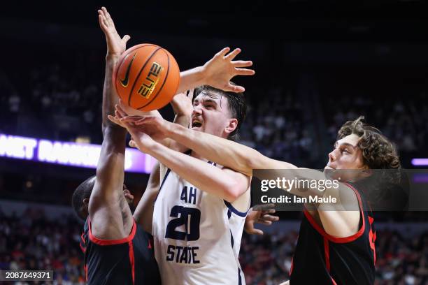 Isaac Johnson of the Utah State Aggies attempts to grab a rebound between Lamont Butler and Miles Heide of the San Diego State Aztecs during the...