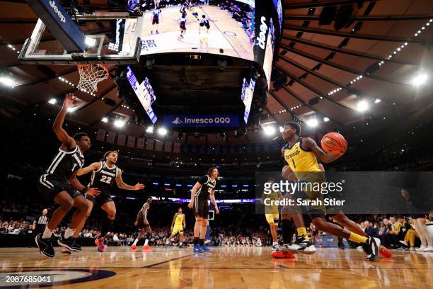 Kam Jones of the Marquette Golden Eagles dribbles toward the basket as Jayden Pierre and Devin Carter of the Providence Friars defend in the second...