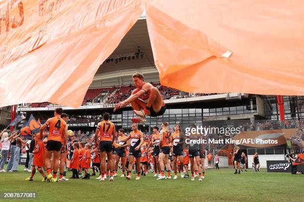 Lachie Whitfield of the Giants prepares to run through their banner during the round one AFL match between Greater Western Sydney Giants and North...