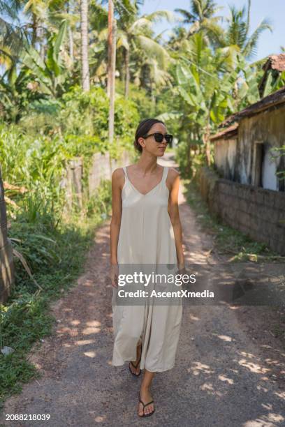 young woman in sundress walks down pathway - vestido de verão imagens e fotografias de stock