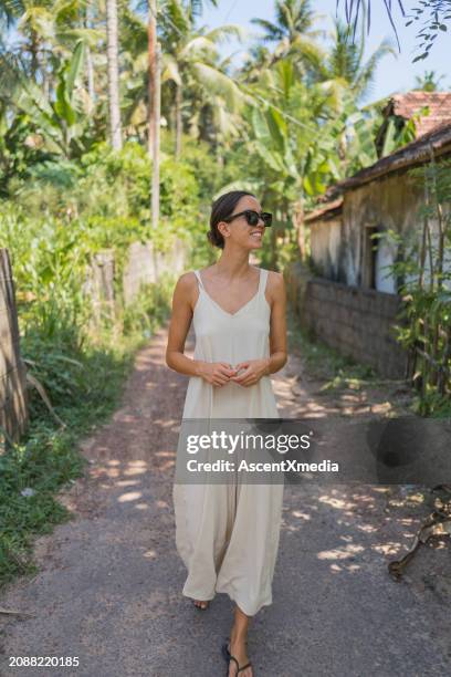 young woman in sundress walks down pathway - vestido de verão imagens e fotografias de stock