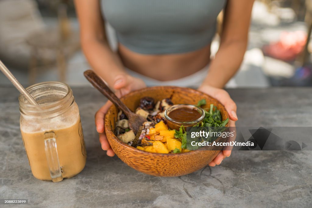 Young woman enjoys vegan salad at outdoor cafe