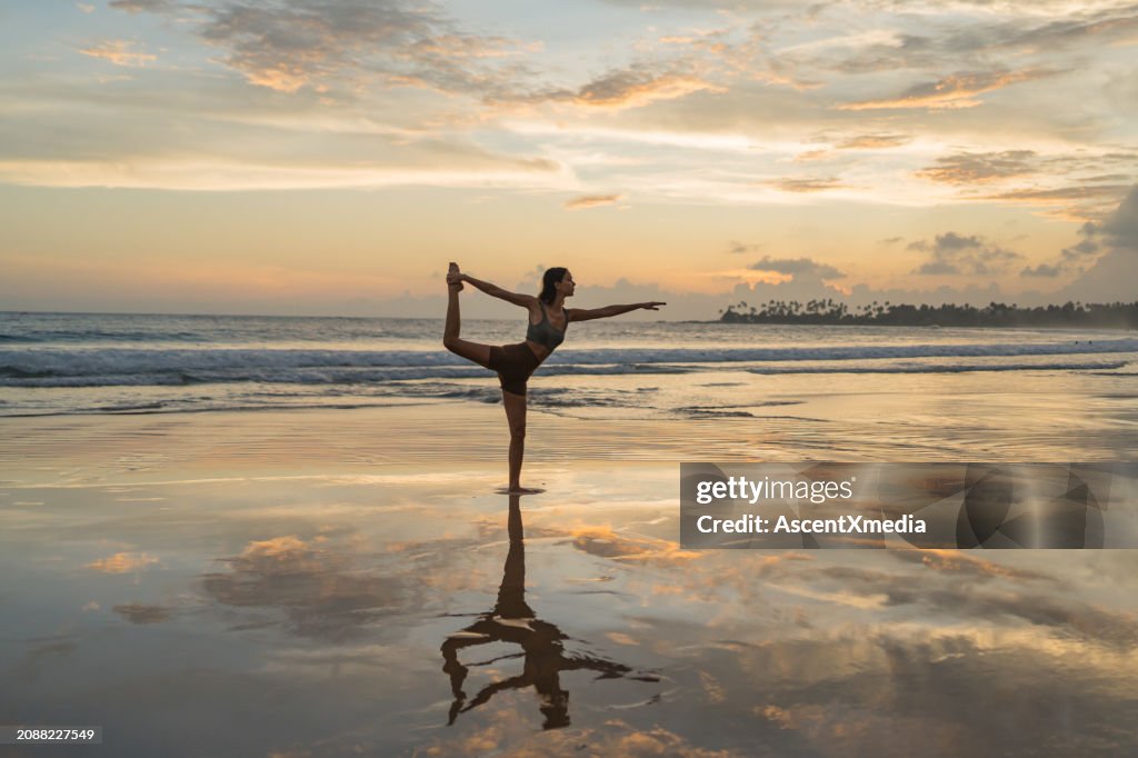 Young woman performs yoga moves on tidal flats