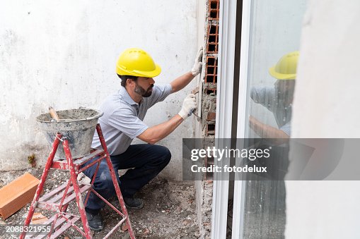 Construction Workers Installing Window Frame on Site Construction Workers Installing Window Frame on Site
