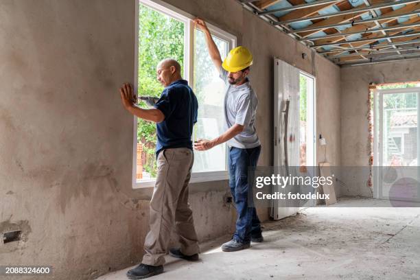 construction workers installing a new window together - restaurar imagens e fotografias de stock