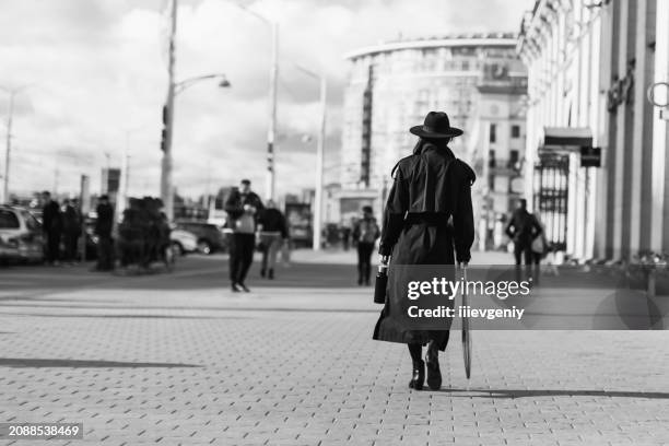 woman in black hat and coat silhouette. noir style. thriller film concept - casacos pretos imagens e fotografias de stock