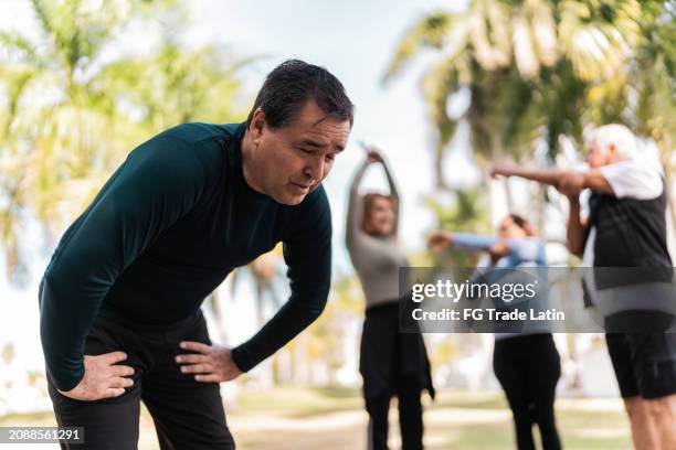 tired mature man after running at public park - hand on knee stock pictures, royalty-free photos & images
