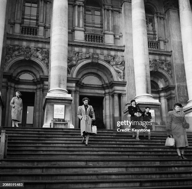 Four women and a young boy on the steps of the Tate Gallery, with posters advertising an exhibition of work by Vincent Van Gogh, on Millbank in...