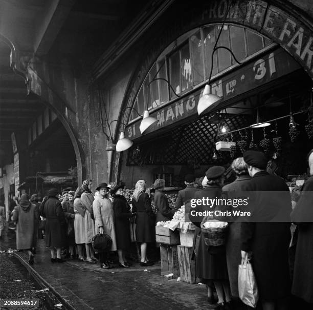 People queue at a market, with food remaining in short supply and some prices being controlled by the Ministry of Food and rationing persists after...