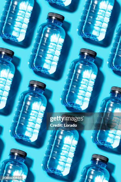 several plastic bottles of water on a colourful background - water bottle stock pictures, royalty-free photos & images