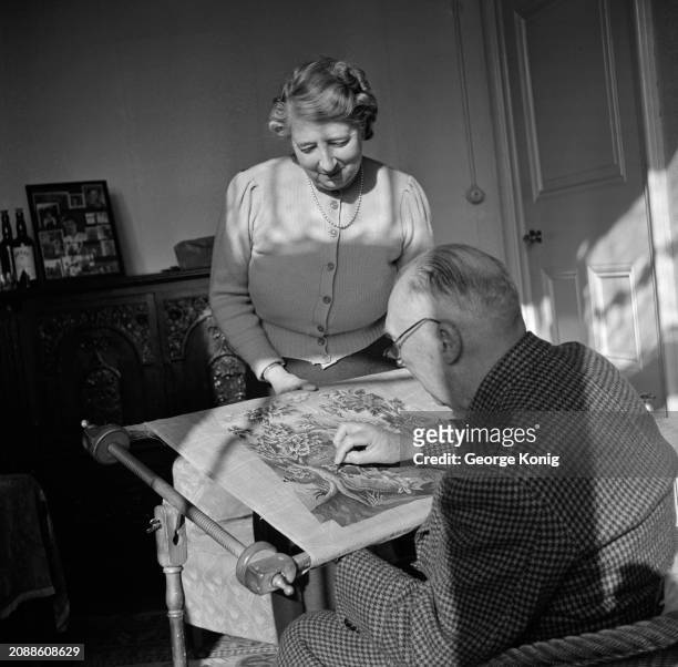 Retired British Army officer Major Martin Crawley-Boevey, at work on a reproduction of a Queen Anne period chair cover, is watched by his wife at...