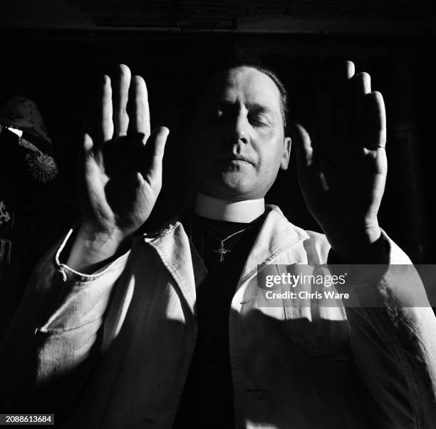 Reverend Harold Nicholson raises his hands during a faith healing service in the crypt beneath a church in Chelsea, London, England, 1948. Nicholson,...