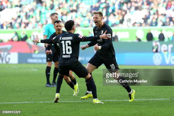 Arne Maier of FC Augsburg celebrates scoring his team's first goal with teammate Ruben Vargas during the Bundesliga match between VfL Wolfsburg and...