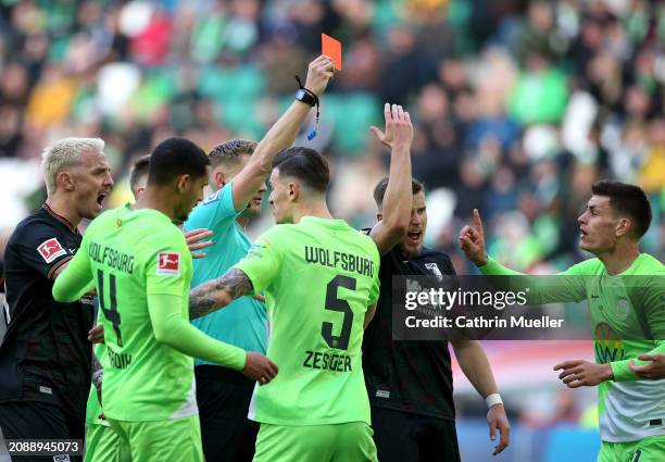 Referee Timo Gerach shows a red card to Patrick Wimmer of VfL Wolfsburg during the Bundesliga match between VfL Wolfsburg and FC Augsburg at...