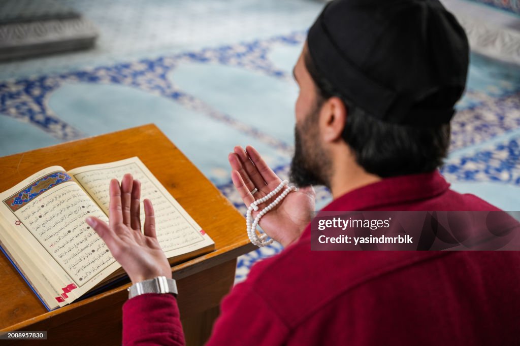 Muslim young man reading Quran praying in mosque