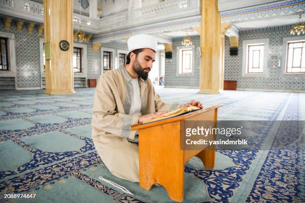 young male imam reading the quran in the mosque during ramadan. - previous stock pictures, royalty-free photos & images