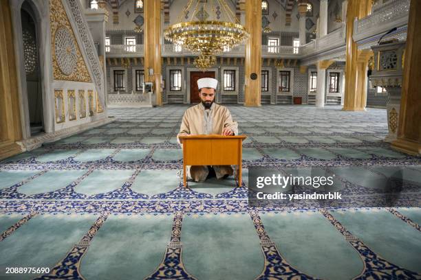 young male imam reading the quran in the mosque during ramadan. - previous stock pictures, royalty-free photos & images